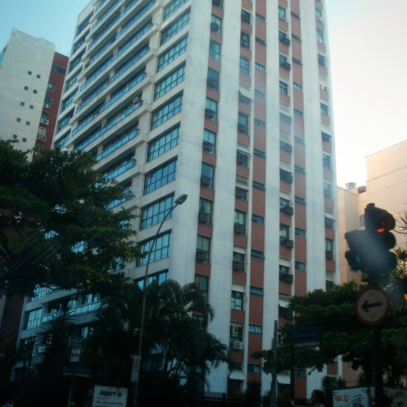 High-rise apartment building with balconies and air-conditioning units on a tree-lined street in Ipanema, Rio de Janeiro