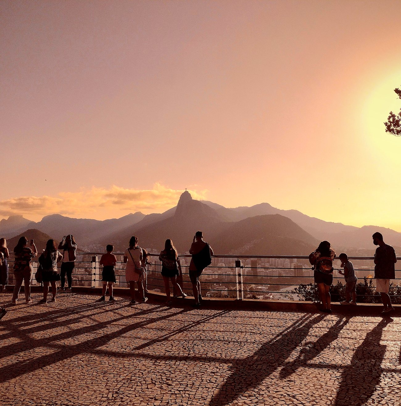 Visitors at a lookout in Urca watching the sun go down behind Corcovado mountain and the Christ the Redeemer statue