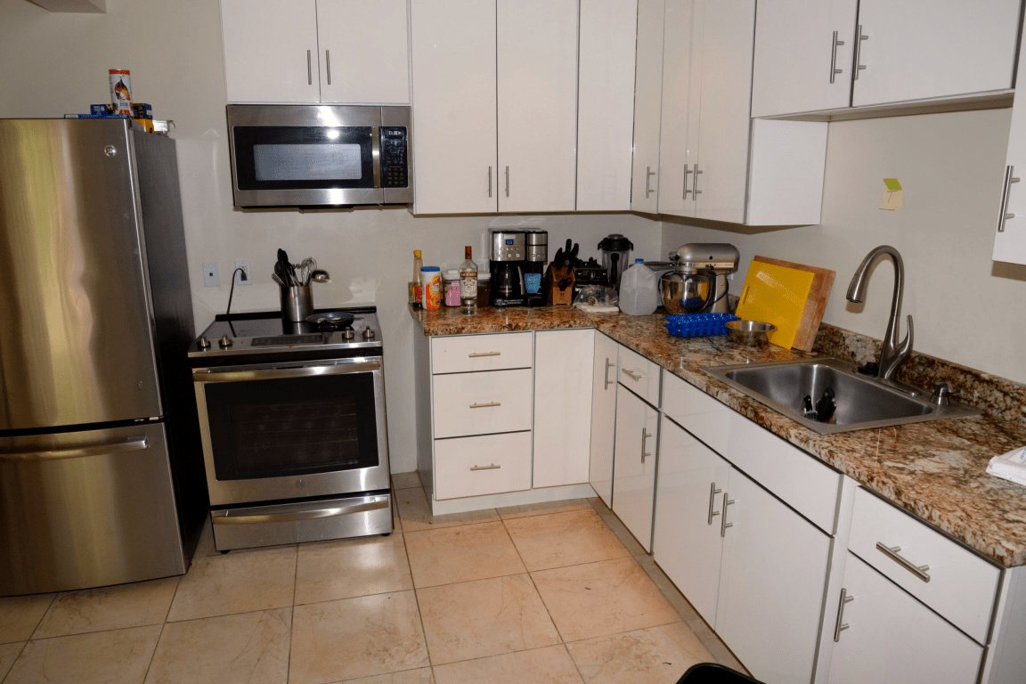 A renovated apartment kitchen with fitted cabinetry and a stone countertop