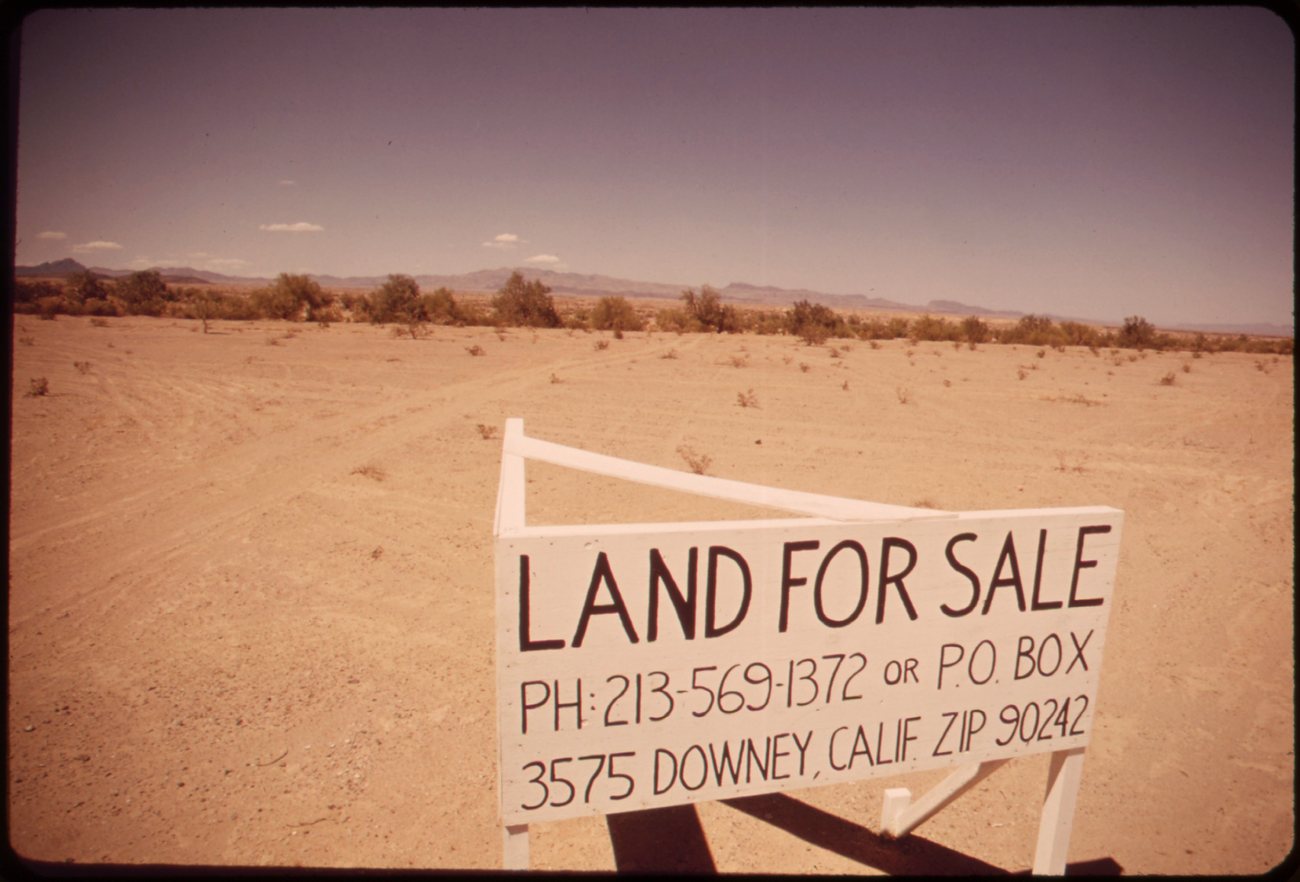 Hands signing a property contract with a pen on paper documents